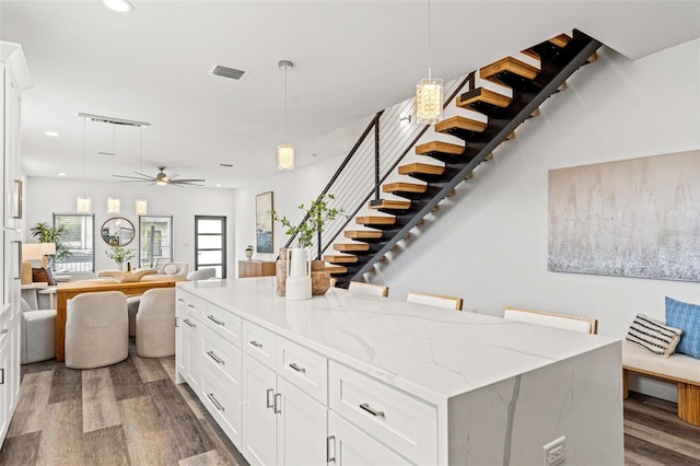 kitchen with white cabinetry, hardwood / wood-style flooring, a center island, and hanging light fixtures