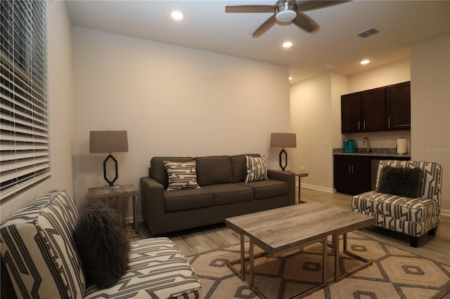 living room featuring sink, light wood-type flooring, and ceiling fan