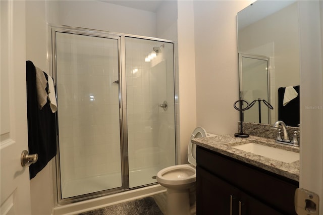 bathroom with vanity, a shower with shower door, and toilet