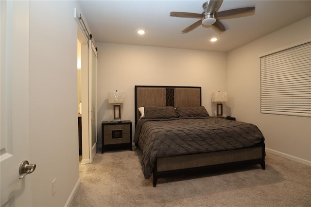 carpeted bedroom featuring a barn door and ceiling fan