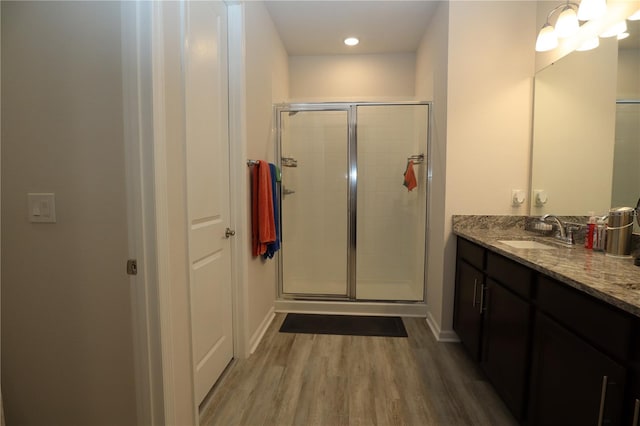 bathroom with a shower with door, hardwood / wood-style floors, and vanity