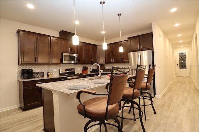 kitchen featuring appliances with stainless steel finishes, sink, hanging light fixtures, and light hardwood / wood-style floors