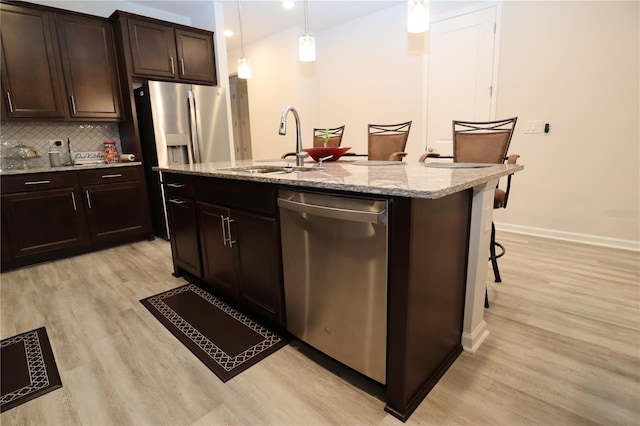 kitchen featuring sink, backsplash, pendant lighting, stainless steel dishwasher, and a center island with sink