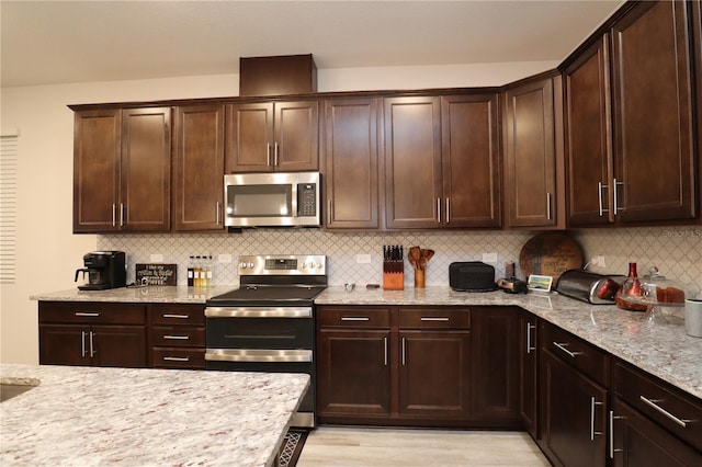 kitchen featuring decorative backsplash, light stone countertops, and stainless steel appliances