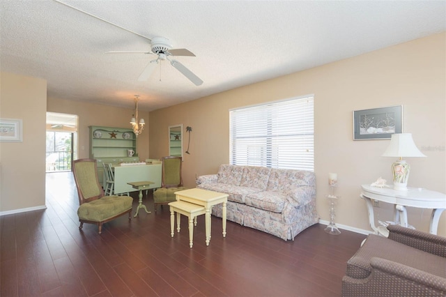 living room with dark wood-type flooring, a textured ceiling, and ceiling fan with notable chandelier