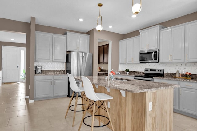 kitchen with white cabinets, stainless steel appliances, and a center island with sink