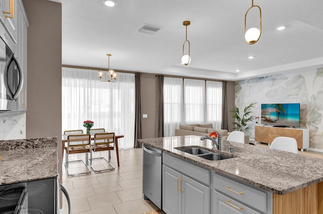 kitchen featuring gray cabinetry, sink, stainless steel appliances, decorative light fixtures, and light stone counters