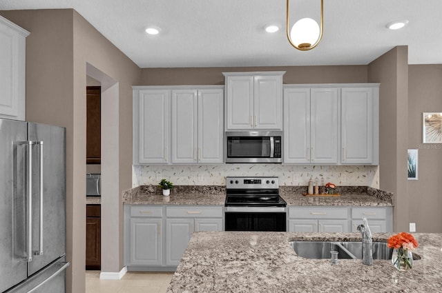 kitchen featuring stainless steel appliances, backsplash, sink, white cabinets, and light stone counters