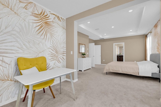 bedroom featuring multiple windows, ensuite bathroom, a tray ceiling, and carpet