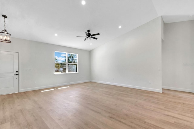 unfurnished living room featuring vaulted ceiling, light hardwood / wood-style flooring, and ceiling fan with notable chandelier