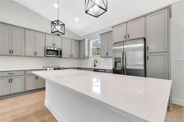 kitchen with a kitchen island, light hardwood / wood-style flooring, hanging light fixtures, vaulted ceiling, and appliances with stainless steel finishes