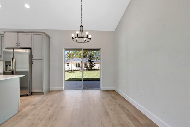 kitchen with hanging light fixtures, gray cabinets, light wood-type flooring, and stainless steel refrigerator with ice dispenser