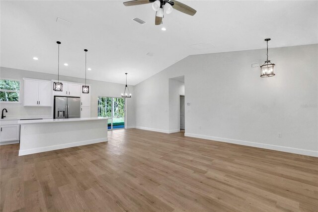 unfurnished living room with lofted ceiling, ceiling fan, light wood-type flooring, and a wealth of natural light