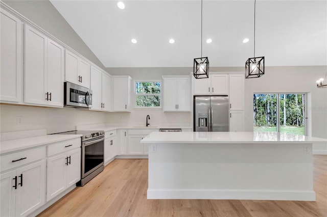 kitchen featuring appliances with stainless steel finishes, a healthy amount of sunlight, a kitchen island, and pendant lighting