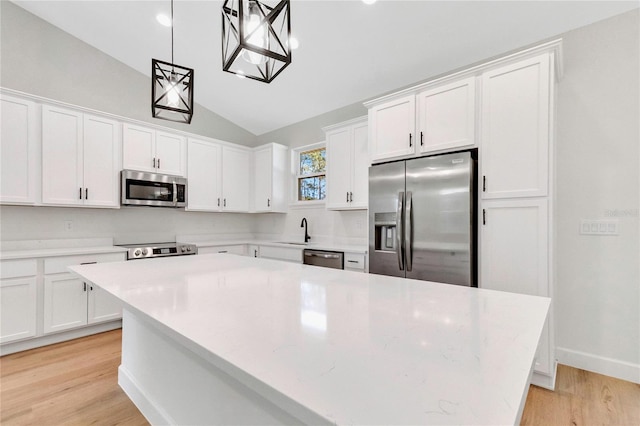 kitchen with white cabinetry, vaulted ceiling, light hardwood / wood-style flooring, stainless steel appliances, and decorative light fixtures