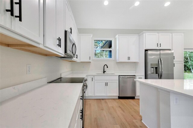 kitchen with sink, appliances with stainless steel finishes, light hardwood / wood-style flooring, and white cabinetry