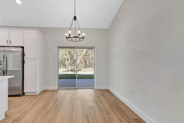 unfurnished dining area featuring lofted ceiling, light hardwood / wood-style flooring, and a notable chandelier