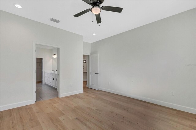 unfurnished bedroom featuring light hardwood / wood-style flooring, ensuite bathroom, and ceiling fan