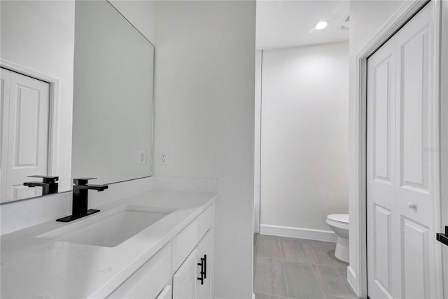 bathroom with toilet, vanity, and tile patterned floors