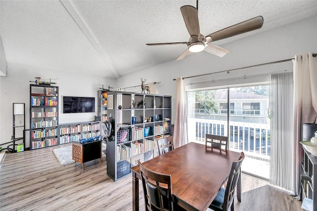 dining room featuring ceiling fan, lofted ceiling, a textured ceiling, and light hardwood / wood-style flooring