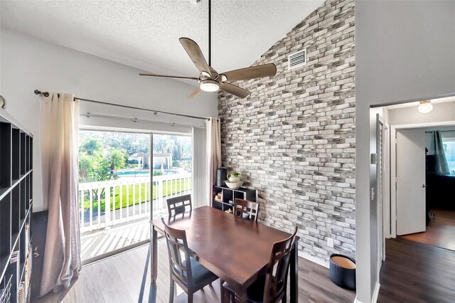 dining room featuring dark hardwood / wood-style floors, ceiling fan, lofted ceiling, and a textured ceiling