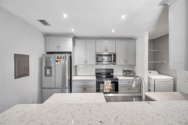 kitchen featuring appliances with stainless steel finishes, gray cabinets, washer / dryer, and sink