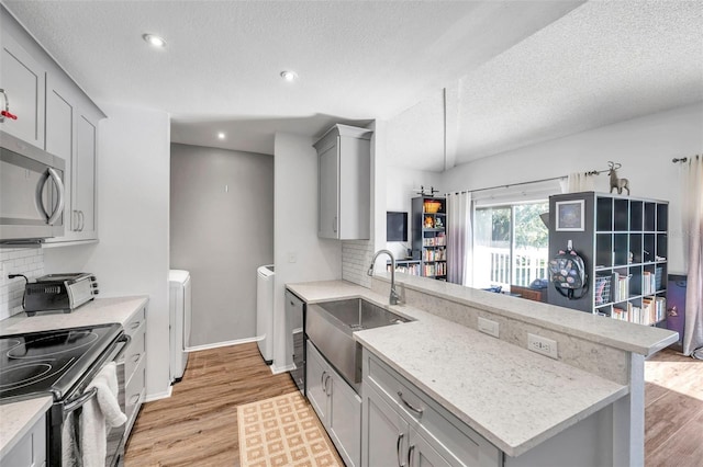 2937 Bough Ave Unit D, Clearwater, FL 33760 - kitchen featuring a sink, separate washer and dryer, gray cabinetry, a peninsula, and stainless steel microwave