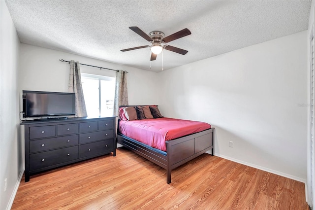 bedroom with a textured ceiling, light hardwood / wood-style flooring, and ceiling fan