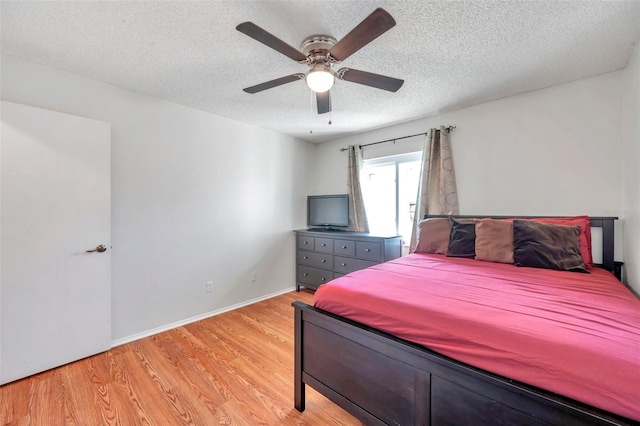 bedroom featuring ceiling fan, light hardwood / wood-style floors, and a textured ceiling