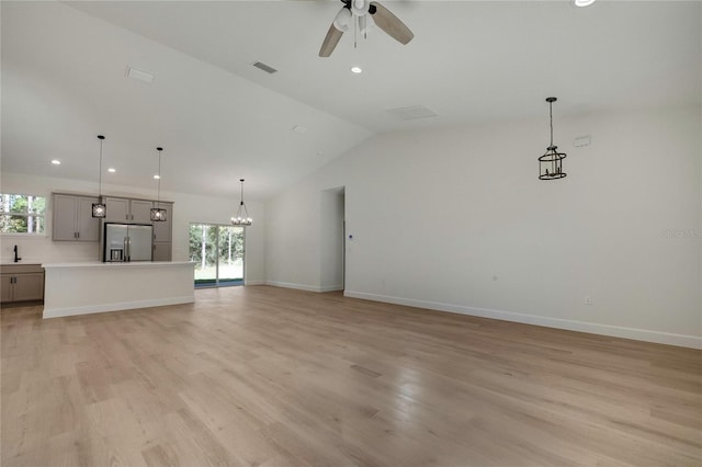 unfurnished living room with light hardwood / wood-style flooring, lofted ceiling, sink, and ceiling fan with notable chandelier