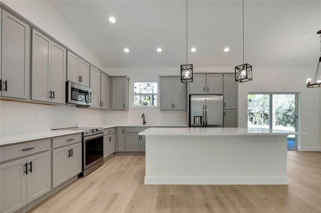 kitchen featuring appliances with stainless steel finishes, gray cabinetry, decorative light fixtures, and a kitchen island