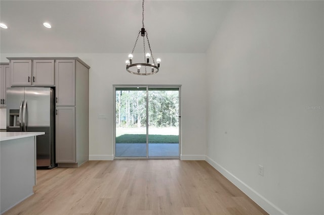 kitchen featuring stainless steel fridge, light hardwood / wood-style floors, decorative light fixtures, gray cabinets, and an inviting chandelier