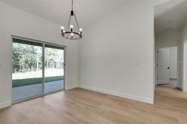 unfurnished room with light hardwood / wood-style flooring, a notable chandelier, and lofted ceiling