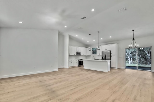 kitchen with a kitchen island, stainless steel appliances, vaulted ceiling, decorative light fixtures, and white cabinetry