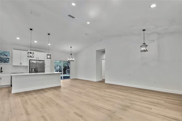 kitchen with light hardwood / wood-style flooring, stainless steel fridge, and decorative light fixtures