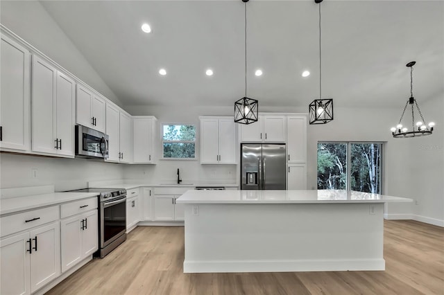 kitchen featuring stainless steel appliances, vaulted ceiling, pendant lighting, and a kitchen island