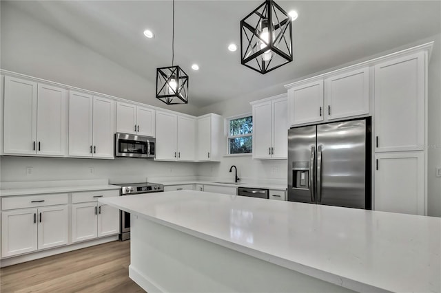 kitchen featuring appliances with stainless steel finishes, white cabinetry, sink, and hanging light fixtures