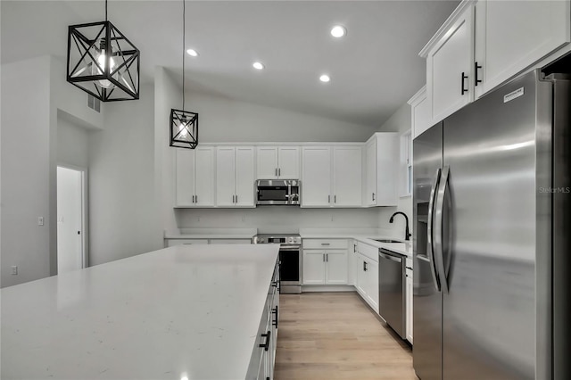 kitchen featuring stainless steel appliances, sink, decorative light fixtures, light wood-type flooring, and white cabinets