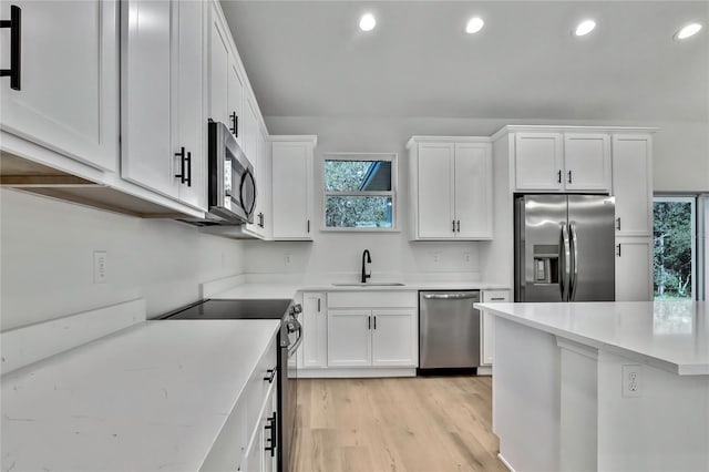 kitchen featuring sink, appliances with stainless steel finishes, white cabinets, and light hardwood / wood-style floors