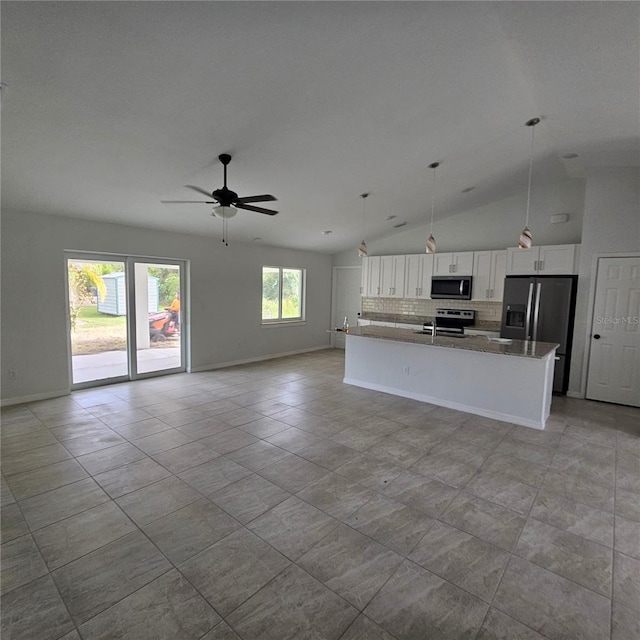 kitchen with hanging light fixtures, dark stone counters, white cabinets, appliances with stainless steel finishes, and high vaulted ceiling