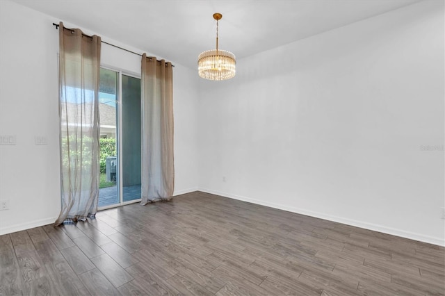 spare room featuring a notable chandelier and hardwood / wood-style flooring