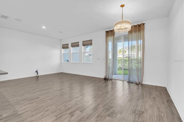 empty room featuring a notable chandelier and wood-type flooring