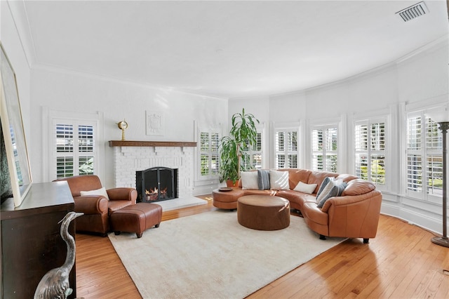 living room featuring ornamental molding, light hardwood / wood-style flooring, and a brick fireplace