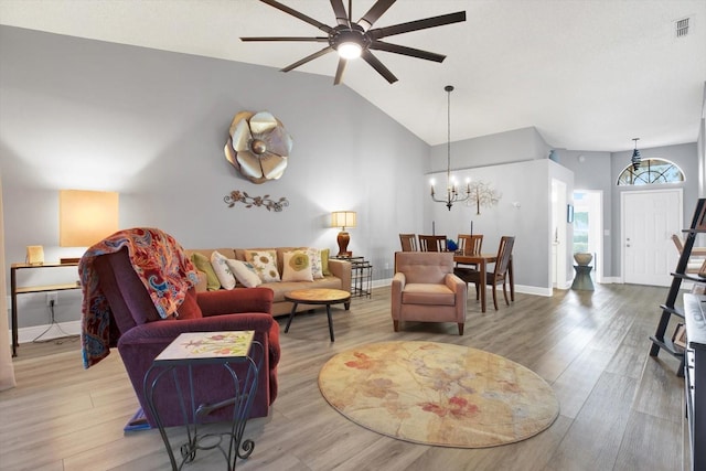 living room with lofted ceiling, wood-type flooring, and ceiling fan with notable chandelier