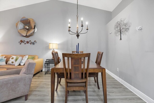 dining area featuring lofted ceiling, a chandelier, and wood-type flooring