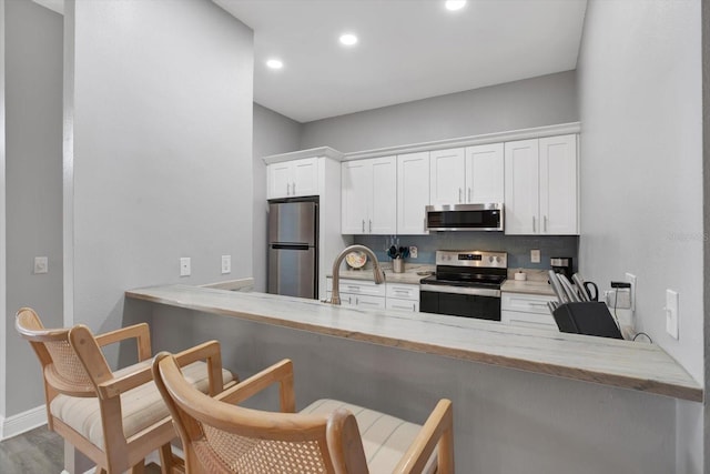 kitchen with stainless steel appliances, white cabinetry, and kitchen peninsula