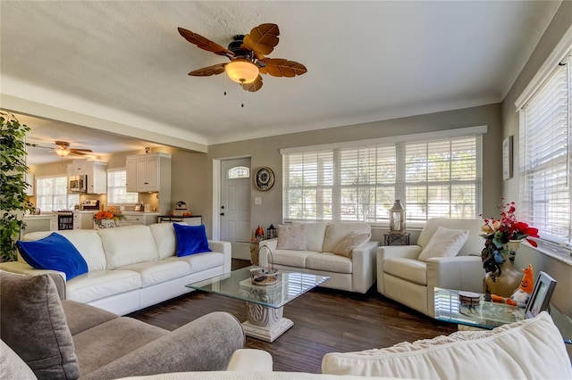 living room featuring dark wood-type flooring, ceiling fan, and plenty of natural light