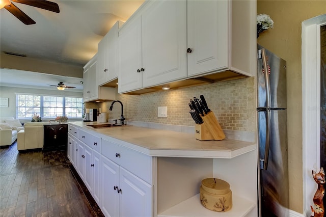 kitchen with dark wood-type flooring, stainless steel refrigerator, white cabinetry, and sink