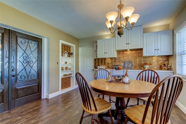 dining area featuring built in shelves, dark wood-type flooring, and a notable chandelier