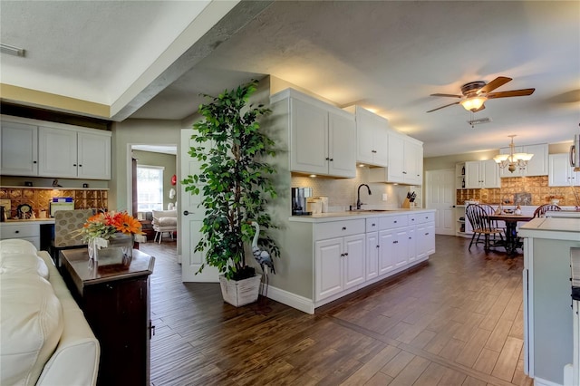 kitchen with pendant lighting, dark wood-type flooring, white cabinets, and sink